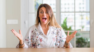 Genç kadın evde çok mutlu ve heyecanlı, kocaman bir gülümseme ile çığlık ve ellerini kaldırdı zaferini kutluyor kazanan ifade