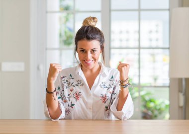 Zafer kutluyor gülümseyen başarı kollarını kaldırdı için genç kadın evde heyecan verici. Kazanan kavramı.