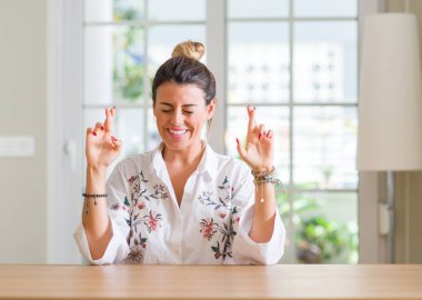 Umut ve gözleri kapalı geçiş parmaklarıyla gülümseyen genç kadın evde. Şans ve batıl kavramı.