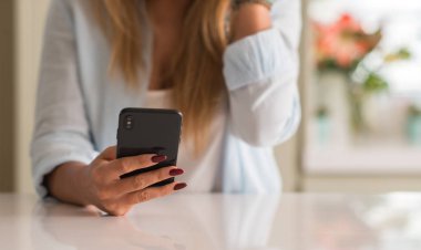 Evde akıllı telefon kullanan bir kadın.