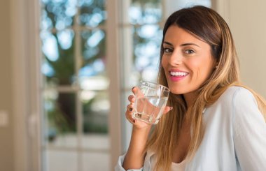 Bir bardak su evde tutarken gülümseyen güzel ve genç birbayan. Yaşam tarzı kavramı.