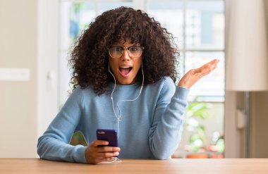 Kocaman bir gülümseme ile çığlık zaferini kutluyor ve ellerini kaldırdı smartphone çok mutlu ve heyecanlı, kazanan ifade kullanan güzel Afrikalı-Amerikalı kadın