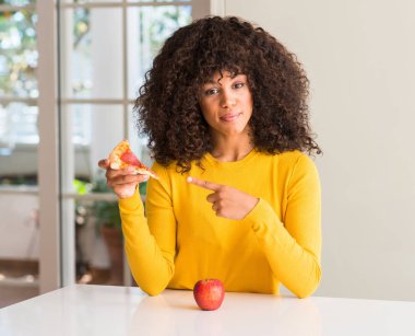 Afrikalı-Amerikalı kadın apple ve pizza dilimi çok mutlu el ve parmak ile işaret arasında seçme