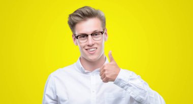 Hareketi el ile mutlu yaşasın yapan genç yakışıklı sarışın erkek. Kameraya bakarak başarı gösteren ile ifade onaylama.