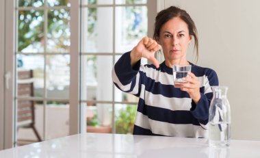 Kızgın yüz, eksi işareti aşağı antipati başparmak ile gösterilen, ret kavramı ile su içme orta yaşlı kadın