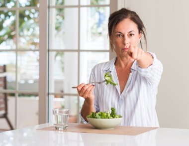 İşareti, pozitif ve kendinden emin bir jest ön el kamera ve size, parmak ile işaret taze salata bir kase içinde evde yemek orta yaşlı kadın