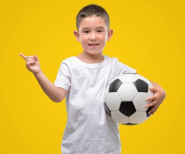Futbol topu el ve parmak ile tarafına işaret çok mutlu ile oynayan koyu saçlı küçük çocuk