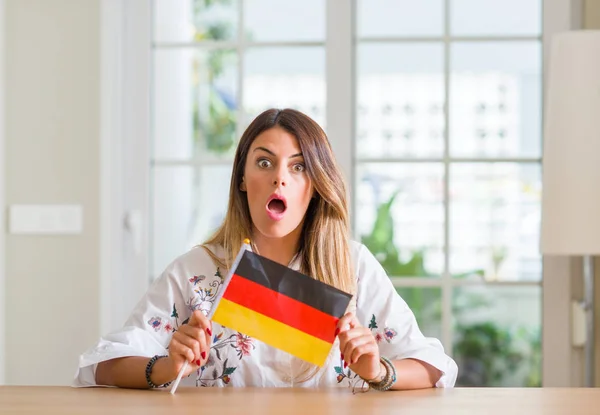 Jovem Mulher Casa Segurando Bandeira Alemanha Assustado Choque Com Rosto — Fotografia de Stock