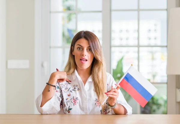 Молодая Женщина Дома Держит Флаг России Неожиданным Лицом Указывающим Пальцем — стоковое фото