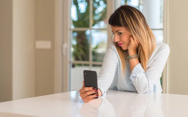 若い女性の幸せな笑顔のスマート フォンを使用して 家庭で見ている携帯電話を保持しています — ストック写真