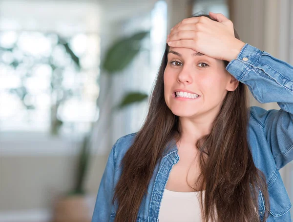 Young beautiful woman at home stressed with hand on head, shocked with shame and surprise face, angry and frustrated. Fear and upset for mistake.