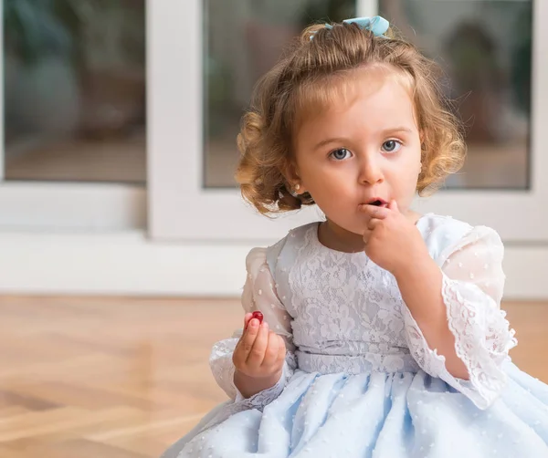 Όμορφο Ξανθό Παιδί Ένα Φόρεμα Που Τρώει Γλυκά Που Κάθεται — Φωτογραφία Αρχείου
