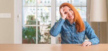 Kızıl saçlı kadın evde gülümseyen, parmakları ile mutlu yüz üzerinden seyir göz el ile ok jest yapıyor.