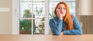 Kızıl saçlı kadın evde seyir yorgun ve çapraz kolları olan depresyon sorunları ile sıkılmış düşünme.