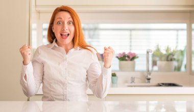 Mutfak kutluyor, Kızıl saçlı kadın şaşırttı ve başarı için kaldırdı kollarını açarak hayret ve gözleri açık. Kazanan kavramı.