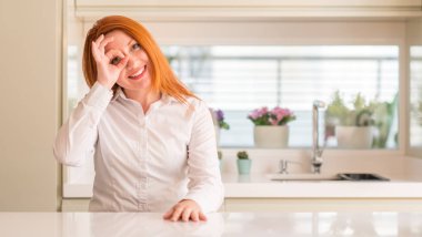 Kızıl saçlı kadın gülümsüyor, parmakları ile mutlu yüz üzerinden seyir göz el ile ok jest yapıyor mutfak at.