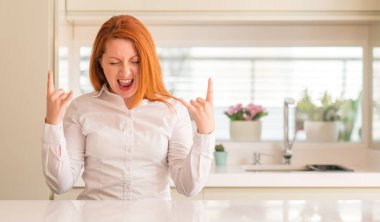 Kızıl saçlı kadın deli ifade rock simge elle yapıyor ile bağırarak mutfak at. Müzik yıldızı. Ağır kavramı.