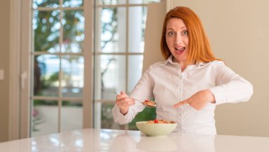 Ev çok mutlu el ve parmak ile işaret ahududu ile tahıl yemek Kızıl saçlı kadın