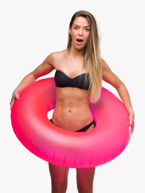 Bikini holding pembe float bir sürpriz yüz, korkuyor ve heyecanlı korku ifadesi ile şok korkmuş güzel genç kadın