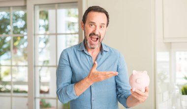 Orta yaş erkek kumbara el ve parmak ile işaret çok mutlu üzerinde tasarruf