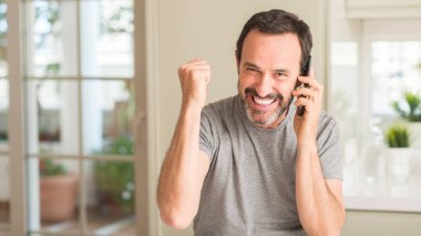 Duygu tezahürat gurur çığlık ve zafer ve başarı çok heyecanlı, kutluyor smartphone kullanarak orta yaş erkek