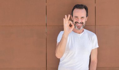 Üst düzey yakışıklı parmak, mükemmel sembolü ile ok işareti yapıyor duvarın üzerinden ayakta