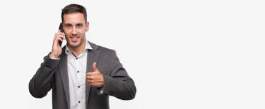 Ok işareti, başparmak ile parmak, mükemmel işareti yapıyor kocaman bir gülümseme ile Smartphone mutlu kullanarak yakışıklı genç