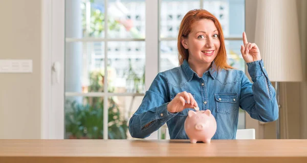 Mulher Ruiva Economiza Dinheiro Mealheiro Casa Surpreso Com Uma Ideia — Fotografia de Stock