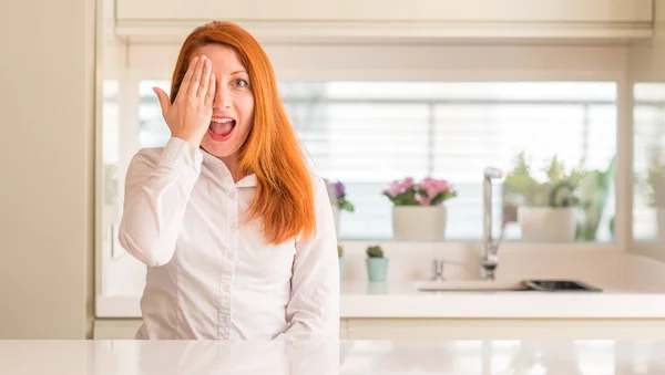 厨房里红头发的女人用手捂着一只眼睛 脸上充满自信的笑容和惊喜的情绪 — 图库照片