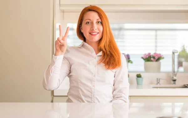 Redhead Woman Kitchen Showing Pointing Fingers Number Two While Smiling — Stock Photo, Image