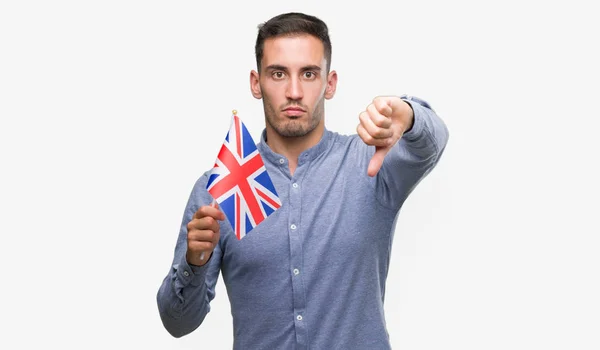 怒った顔 ダウン親指で嫌悪感を示すマイナス記号 拒絶反応の概念はイギリスの旗を保持しているハンサムな若い男 — ストック写真