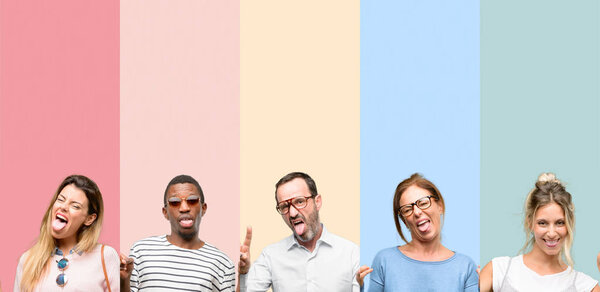 Смешанная группа людей, женщин и мужчин, смотрящих в камеру, показывающих язык и делающих знак победы пальцами
