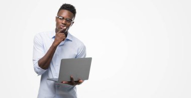 Bilgisayar dizüstü ciddi bir yüz düşünme soru hakkında çok kullanarak genç Afro-Amerikalı iş adamı fikri karıştı