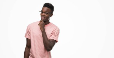 Emin çapraz kollar ve çeneme kaldırdı el ile gülümseme ile kameraya bakarak pembe t-shirt giyen genç Afro-Amerikan adam. Pozitif düşünce.