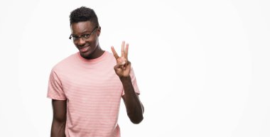 Gösterilen ve parmakları ile işaret pembe t-shirt giyen genç Afro-Amerikan adam kendinden emin ve mutlu gülümseyerek iken üçüncü.