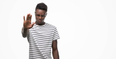 Gözlük ve lacivert t-shirt giyen genç Afro-Amerikan adam elin avuç ile şarkı stop yapıyor. Negatif ve ciddi bir jest yüz ifadesiyle uyarı.