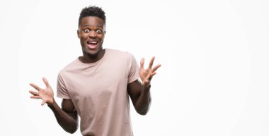 Genç Afro-Amerikan adam çok mutlu ve heyecanlı, kazanan ifade büyük gülümseme ile çığlık ve ellerini kaldırdı zaferini kutluyor