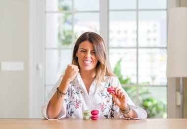 Genç kadına ev yeme macarons rahatsız ve öfkeyle, çılgın ve yükseltilmiş eliyle diye bağıran öfke kavramı bağırarak boşa