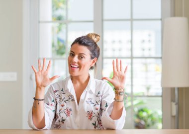 Genç kadın evde gösterilen ve parmak sayısı on kendinden emin ve mutlu gülümseyerek süre ile yukarı dönük.