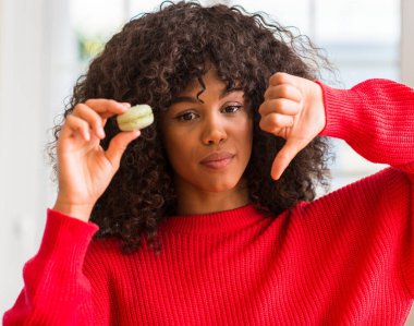 African american woman holding macaron with angry face, negative sign showing dislike with thumbs down, rejection concept clipart