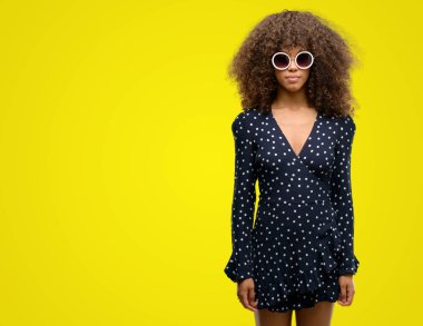 Afrikalı-Amerikalı kadın güneş gözlüğü ve yaz elbise acımak yüz düşünme ciddi kendine güvenen bir ifade ile