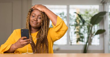 Baş, el ile vurguladı kulaklık ile akıllı telefon kullanan Afrikalı-Amerikalı kadın şok utanç ve sürpriz suratla, öfkeli ve sinirli. Korku ve hata için üzgün.