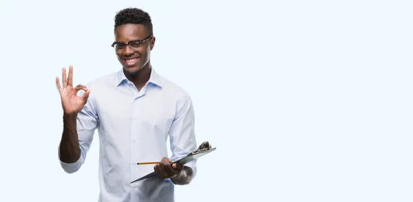 Young African American Man Holding Clipboarad Doing Sign Fingers Excellent — Stock Photo, Image