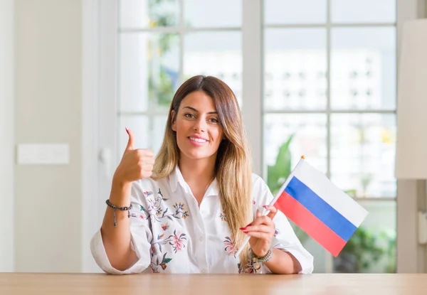 若い女性自宅 サインをして笑顔で幸せなロシアの旗を保持している優秀な兆候の指で親指 — ストック写真