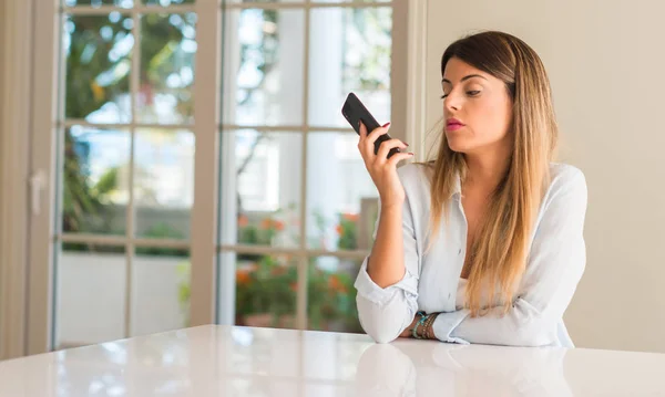 Disgusted woman using smartphone, holding mobile phone, looking at home