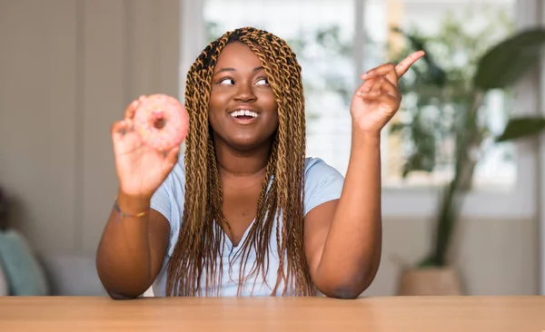 Afrikanerin Isst Donut Sehr Glücklich Und Zeigt Mit Hand Und — Stockfoto