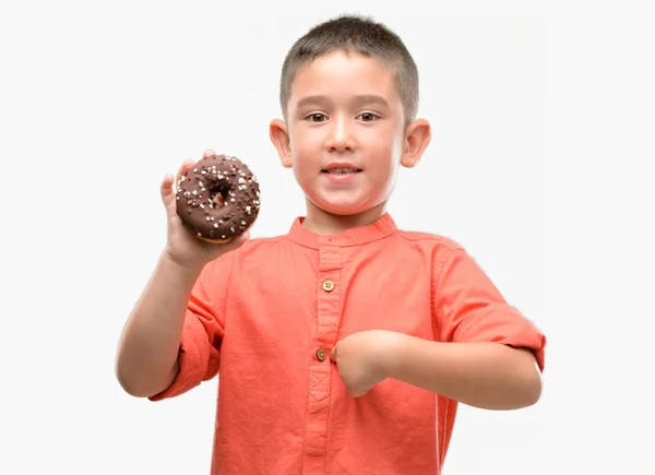 Niño Moreno Comiendo Donut Con Cara Sorpresa Apuntándose Con Dedo — Foto de Stock