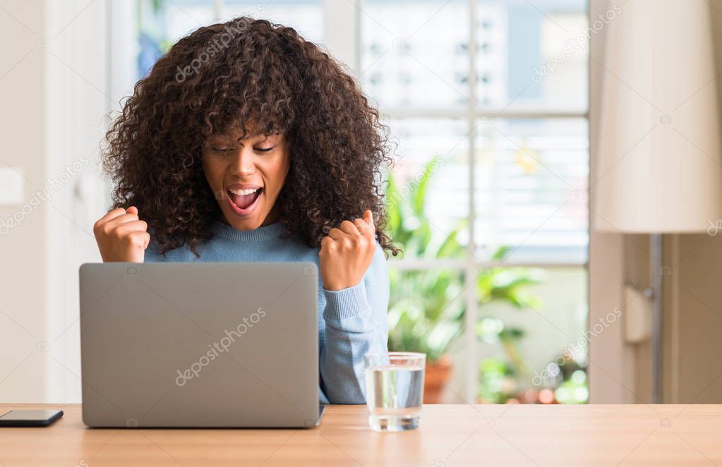 African american woman using laptop computer at home screaming proud and celebrating victory and success very excited, cheering emotion