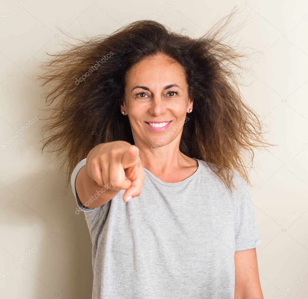Curled hair brazilian woman pointing with finger to the camera and to you, hand sign, positive and confident gesture from the front
