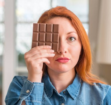 Acımak yüz ciddi düşünüyorum üstünde kendine güvenen bir ifade ile evde çikolata bar tutan Kızıl saçlı kadın